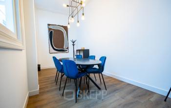 Meetingruimte met moderne inrichting op Keizersgracht 452, Amsterdam Grachtengordel. Blauwe stoelen rondom een ovale tafel onder een stijlvolle lamp. Ideaal voor kantoorruimte huur voor bedrijven.