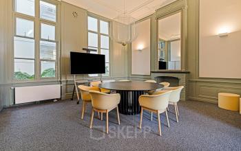 Vergaderruimte met ronde tafel en stoelen, een televisie aan de muur, in het kantoorpand aan Keizersgracht 572 572 in Amsterdam Grachtengordel te huur.