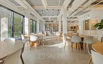 Ruime, lichte werkplek in Amsterdam Grachtengordel met modern meubilair en grote raampartijen, ideaal om een kantoor te huren voor creatieve en zakelijke doeleinden.