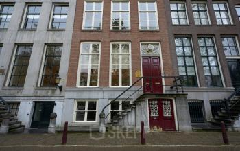 Buitenkant van het kantoorpand gelegen op Keizersgracht 391A in Amsterdam Grachtengordel. Het historische gebouw heeft grote ramen en een klassieke rode deur, ideaal voor wie kantoorruimte wil huren.