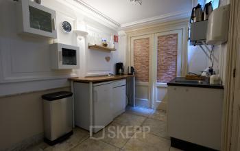 Compacte pantry in kantoorpand op Keizersgracht 391A, Amsterdam Grachtengordel, met keukenkastjes, aanrecht en koffiezetapparaat, ideaal voor korte pauzes tijdens het kantoorwerken.