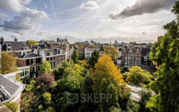 Buitenzijde van kantoorpand aan de Herengracht 582-584 in de Amsterdamse Grachtengordel, met omliggende groene bomen en historische gebouwen.