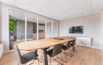 Moderne kantoorruimte huren aan de Herengracht in Amsterdam Grachtengordel met een vergadertafel, stoelen en glazen scheidingswanden.
