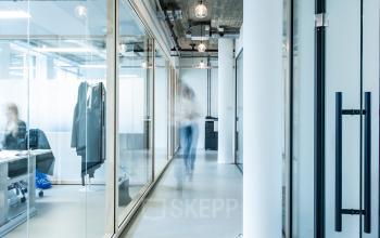 Modern kantoorpand op Singel 542 in Amsterdam Grachtengordel, met glazen wanden en zichtbare industriële elementen. Personen werken aan bureaus in een lichte ruimte.