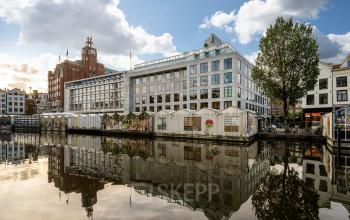Kantoorpand aan de Singel 542, Amsterdam Grachtengordel, gelegen aan het water. Geschikt voor kantoorruimte huren. Moderne architectuur met grote ramen en een reflectie in de gracht.