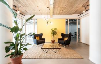 Moderne kantoorruimte met comfortabele stoelen en glazen tafel, omgeven door planten, te huur op Singel 542 in de Amsterdam Grachtengordel.