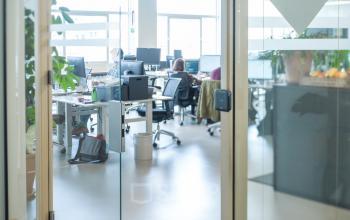 Moderne kantoorruimte op Singel 542 in Amsterdam Grachtengordel, met verschillende personen aan het werk. De ruimte is voorzien van werkplekken met bureaus en stoelen.