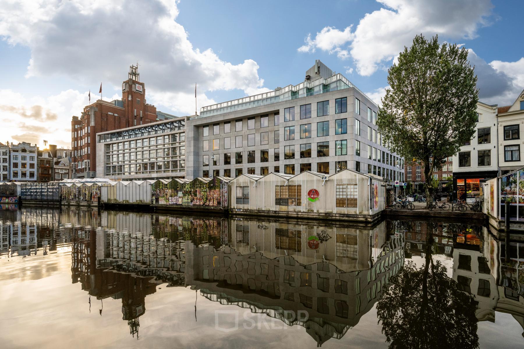 Kantoorpand aan de Singel 542, Amsterdam Grachtengordel, gelegen aan het water. Geschikt voor kantoorruimte huren. Moderne architectuur met grote ramen en een reflectie in de gracht.