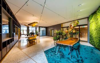 Ruime en moderne entree van kantoorpand op Herengracht 459-469, Amsterdam Grachtengordel, met stijlvolle houten tafels, groene accenten en planten, ideaal voor kantoorruimte huren.