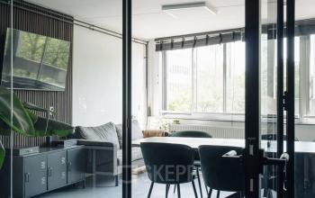 Kantoorruimte aan Weesperstraat 394-396, Amsterdam Grachtengordel, met glazen wanden, een tafel met stoelen en natuurlijke lichtinval. Ideaal voor kantoor huren of vergaderingen.