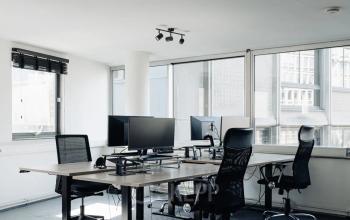 Lichte kantoorruimte huren op Weesperstraat 394-396 in Amsterdam Grachtengordel met bureaus, stoelen en computers klaar voor gebruik in een moderne setting.