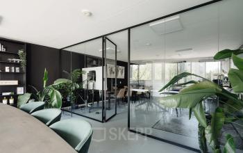 Moderne kantoorruimte in Amsterdam Grachtengordel aan de Weesperstraat 394-396, met glazen wanden, groene planten en stijlvolle meubilair. Ideale plek voor creatief werken en huren.