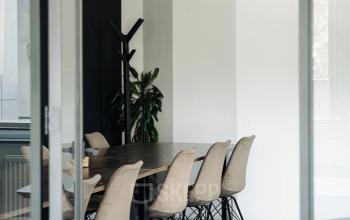 Een moderne ruimte in een kantoorpand op Weesperstraat 394-396, Amsterdam Grachtengordel. Het interieur is gemeubileerd met een grote tafel en comfortabele stoelen, geschikt voor vergaderingen.