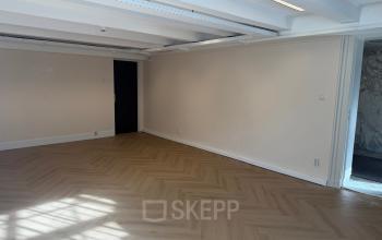 Lichte kantoorruimte op Herengracht 493 met houten vloer en witte wanden, ideaal om zelf in te richten. Grote ramen laten veel natuurlijk licht binnen.