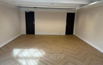 Leeg kantoor op Herengracht 493, Amsterdam Grachtengordel, met houten visgraat vloer en witte muren.