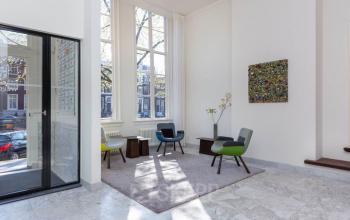 Interieur van het kantoorpand op Keizersgracht 97-99, Amsterdam Grachtengordel, met een lichte ontvangstruimte met zitgedeelte bij grote ramen.