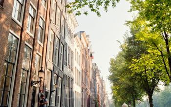 Buitenaanzicht van een kantoorpand aan de Keizersgracht 106 in Amsterdam Grachtengordel. Klassieke grachtenpanden en bomen langs de gracht.