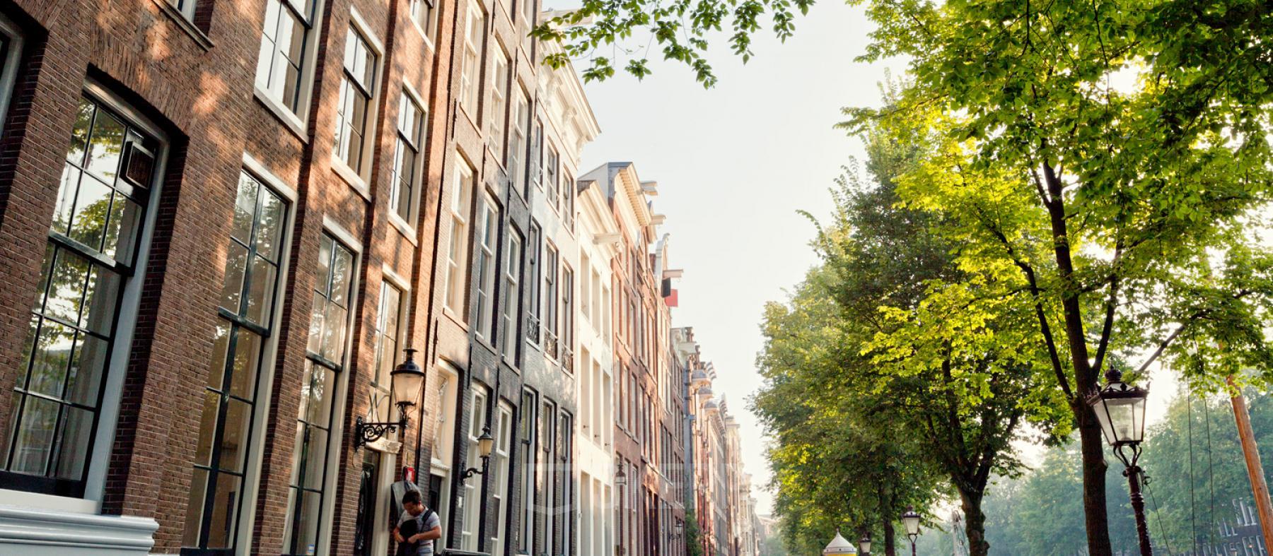 Buitenaanzicht van een kantoorpand aan de Keizersgracht 106 in Amsterdam Grachtengordel. Klassieke grachtenpanden en bomen langs de gracht.