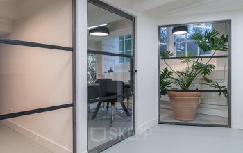 Moderne kantoorruimte met glazen wanden op Herengracht 168 in Amsterdam Grachtengordel, licht en planten aanwezig.