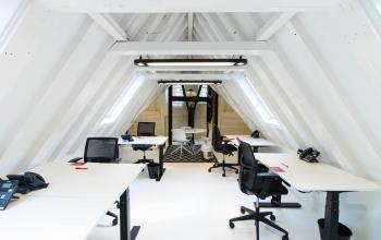 Kantoorruimte huren in een moderne, strakke zolderetage met witte balken en vier bureaus, gelegen aan de Herengracht 280 in de Amsterdam Grachtengordel.