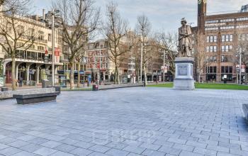 Exterieur van het kantoorpand Amstel 62 in de Amsterdam Grachtengordel, omgeven door historische gebouwen en een open plein met standbeeld.