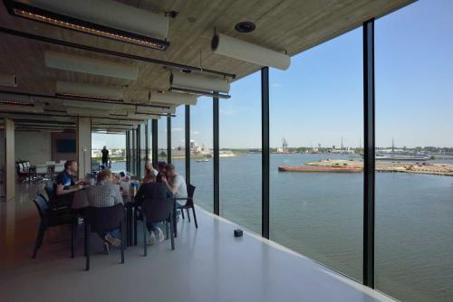 Mensen zitten aan een tafel in een ruim, modern kantoor aan de Moermanskkade 109-113, Amsterdam Houthavens, met uitzicht op het water, ideaal voor kantoorruimte huren.