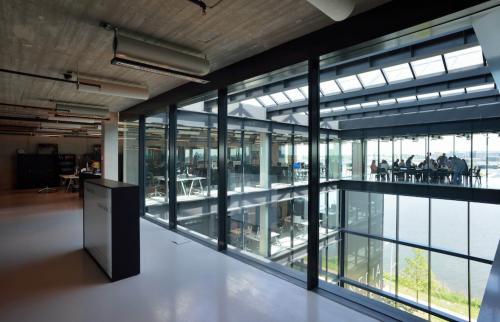 Kantoorpand op Moermanskkade 109-113 in Amsterdam Houthavens, met moderne glazen gevels en natuurlijke lichtinval. Mensen werken achter bureaus in een open omgeving. Ideale kantoorruimte huren in Amsterdam.