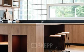 Moderne kantoorruimte met stijlvolle bar en krukken, hoge ramen en warme houttinten op de Overschiestraat 65, ideaal voor wie een kantoor wil huren in Amsterdam Nieuw-West.