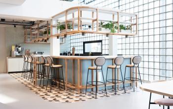 Moderne gecombineerde pantry en lounge in een kantoor op Overschiestraat 63, Amsterdam Nieuw-West met hoge krukken en planten.