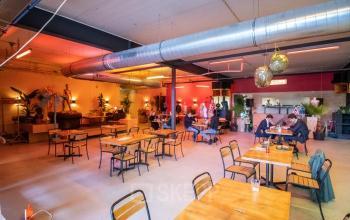 Interieur van een gemeubileerd kantoorpand aan de Anthony Fokkerweg 3 in Amsterdam Nieuw-West, met verschillende werkplekken en mensen in overleg. Ideaal voor kantoorruimte huren in een dynamische omgeving.