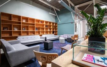 Kantoorruimte huren aan de Anthony Fokkerweg 3 in Amsterdam Nieuw-West met moderne lounge, stijlvolle zitbanken en houten planken, ideaal voor informele bijeenkomsten en ontspanning.