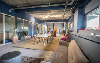 Kantoorruimte huren aan de Anthony Fokkerweg 3, Amsterdam Nieuw-West, met open indeling en moderne inrichting, inclusief grote ramen en zitgedeelte. Ideaal voor creatieve werkomgeving.