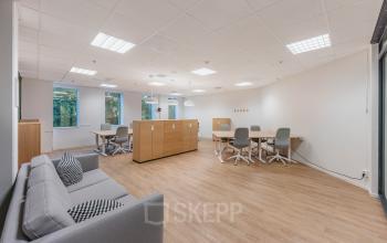 Ruime, lichte kantoorruimte huren op Koningin Wilhelminaplein 1, Amsterdam Nieuw-West. Voorzien van comfortabele werkplekken, houten vloer en moderne inrichting met uitzicht op een groene omgeving.