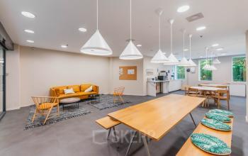 Moderne gemeubileerde kantoorruimte op Koningin Wilhelminaplein 1 in Amsterdam Nieuw-West, met zithoek en keukenvoorzieningen, ideaal om te huren voor creatieve samenwerking en ontspanning.