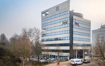 Kantoorpand aan de Overschiestraat 61 in Amsterdam Nieuw-West, met meerdere verdiepingen en parkeerplaatsen voor de deur.