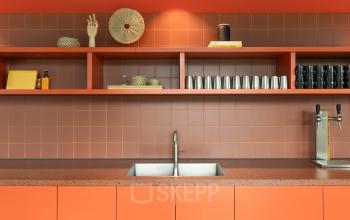 Moderne, oranje pantry in kantoorpand Papaverhof 58 in Amsterdam Noord met minimalistische inrichting en keukenapparatuur. Ideaal voor korte pauzes tijdens het kantoorwerk.