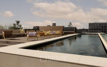 Dakterras met houten stoelen en een vijver bij kantoorpand Papaverhof 58, Amsterdam Noord, ideaal voor werkpauzes en netwerkbijeenkomsten.