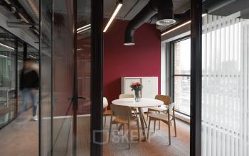 Moderne kantoorruimte op Papaverhof 58 in Amsterdam Noord met een ronde tafel en stoelen, ideaal voor vergaderingen. Grote ramen zorgen voor veel natuurlijk licht.