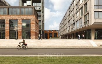Exterieur van moderne kantoren op Papaverhof 58, Amsterdam Noord, met enkele voetgangers nabij de ingang. Ideaal voor kantoorruimte huren.