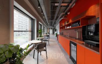 Moderne en stijlvolle pantry op Papaverhof 58 in Amsterdam Noord, ideaal voor bedrijven die kantoorruimte huren zoeken. Voorzien van feloranje elementen en grote ramen met uitzicht.