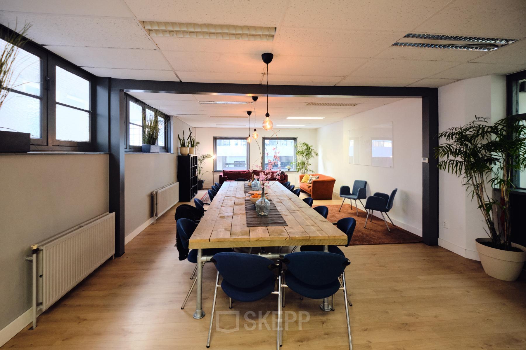 Ruime kantoorruimte huren in Amsterdam Noord op Hamerstraat 24. Gezellige werkplek met lange tafel omringd door stoelen en veel natuurlijk licht. Ideaal voor creatieve samenwerking en vergaderingen.