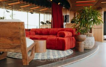 Moderne kantoorruimte met een rode bank en houten elementen op Overhoeksplein 1 in Amsterdam Noord. Ideaal om te huren voor zakelijke bijeenkomsten in een stijlvolle setting.