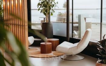 Stijlvolle kantoorruimte huren in Amsterdam Noord met comfortabele stoelen, houten elementen en veel groen. Ideaal voor informele vergaderingen of ontspanning tussen het werk door.