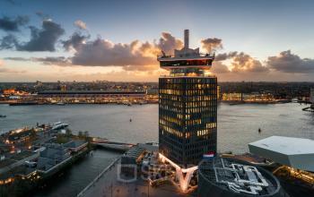 Panoramisch uitzicht op het kantoorgebouw aan Overhoeksplein 1 in Amsterdam Noord, gelegen aan het water met een indrukwekkend stadsgezicht op de achtergrond.