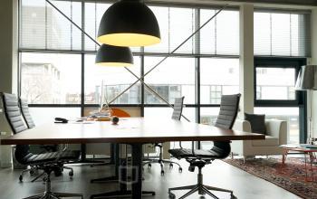 Moderne vergaderruimte met grote tafel en designverlichting in kantoorpand op Asterweg 19, Amsterdam Noord, met zichtbaar stedelijk uitzicht.