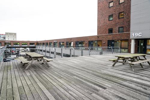 Modern kantoorpand op Asterweg 19, Amsterdam Noord, met houten terras en picknicktafels voor zakelijke ontspanning of informele meetings.