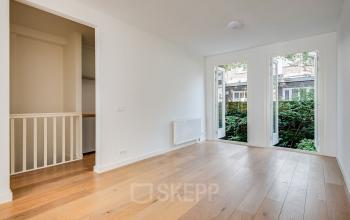 Lichte, open kantoorruimte met houten vloer en grote ramen aan de Domselaerstraat 27 in Amsterdam Oost, ideaal voor startende ondernemers die een kantoorruimte willen huren.