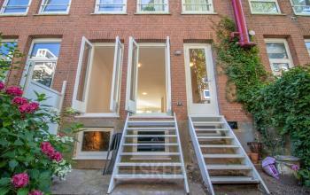 Buitenzijde van kantoorpand aan Domselaerstraat 27 in Amsterdam Oost met twee witte trapopgangen en bloemen aan de zijkant.