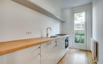 Keukenruimte in kantoorpand aan de Domselaerstraat 27 in Amsterdam Oost met houten werkblad en witte kasten.