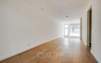 Lichte kantoorruimte aan de Domselaerstraat 27 in Amsterdam Oost, klaar voor huur en inrichting. De ruimte biedt een houten vloer en een groot raam voor natuurlijk licht.